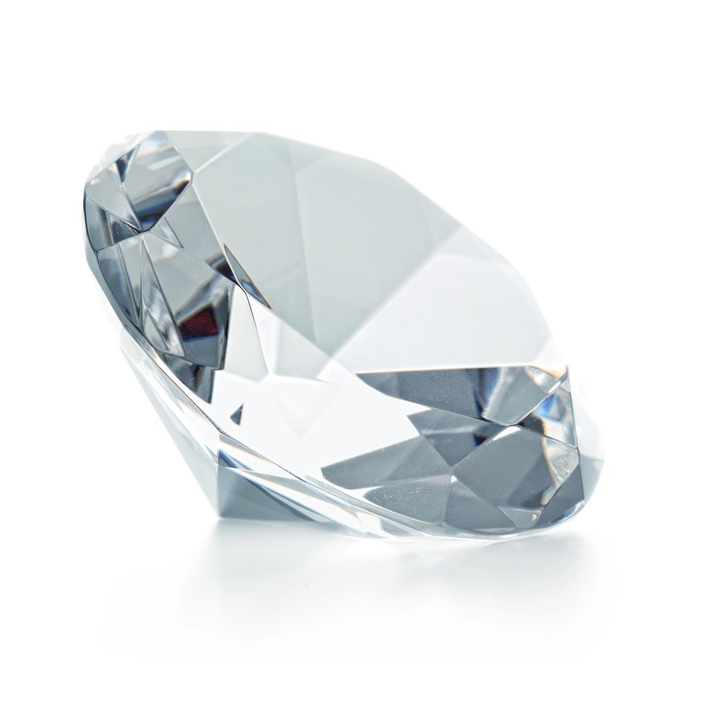 Close-up of a sparkling, faceted diamond on a white surface.