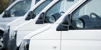 A row of white vans parked closely together outdoors.