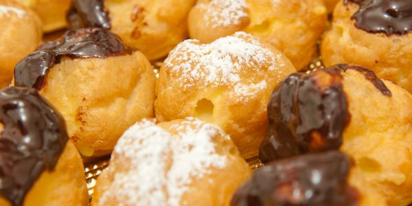 Assorted cream puffs topped with powdered sugar and chocolate glaze.