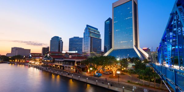 City skyline at dusk with river and bridge.