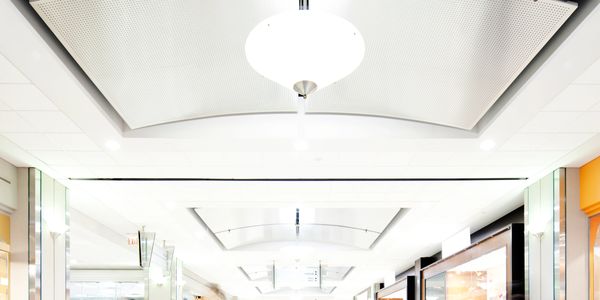 Bright, modern shopping mall corridor with various stores and ceiling lights.