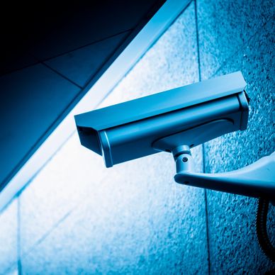 Close-up of a security camera mounted on a blue wall.