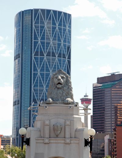 Stone lion statue in front of a modern skyscraper.