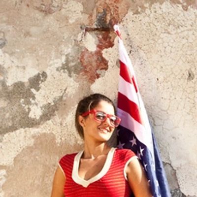 Woman in red top and sunglasses with a flag.