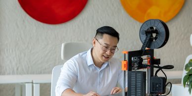 Man working with a 3D printer in a modern workspace.