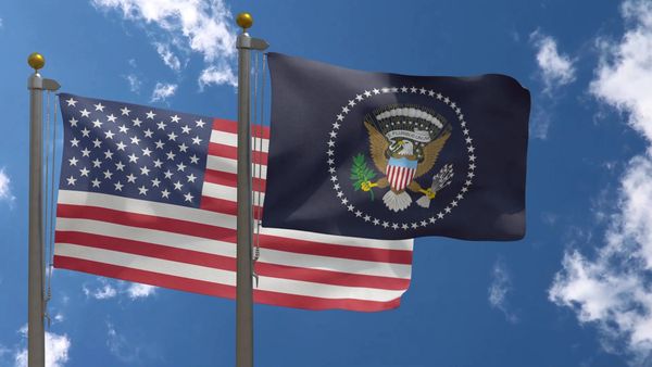 U.S. flag and Navy flag waving against a blue sky with clouds.