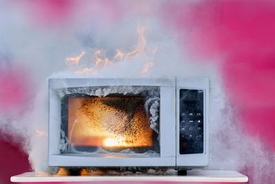 Microwave oven on fire with smoke.