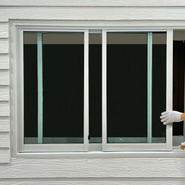Hand sliding open a white-framed window on a white wall.