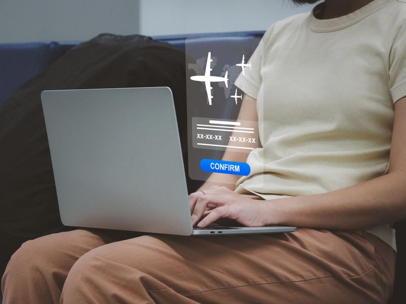 young woman confirming flight booking Confirm your trip with the airline. through an application on a laptop