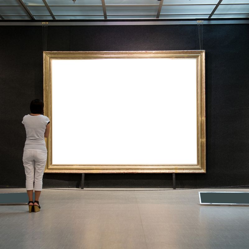 woman looking at white frames in an art gallery.