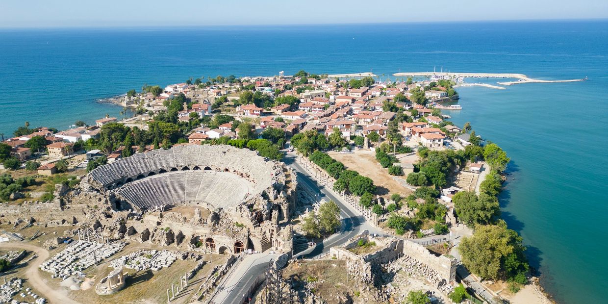 Aerial view of an ancient amphitheater and coastal town by the sea.
