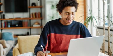 Young man studying with laptop and notebook.
