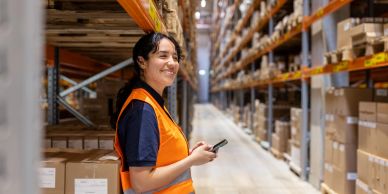 Smiling warehouse worker holding a phone.