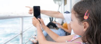 Girl taking a photo with her phone on a boat.