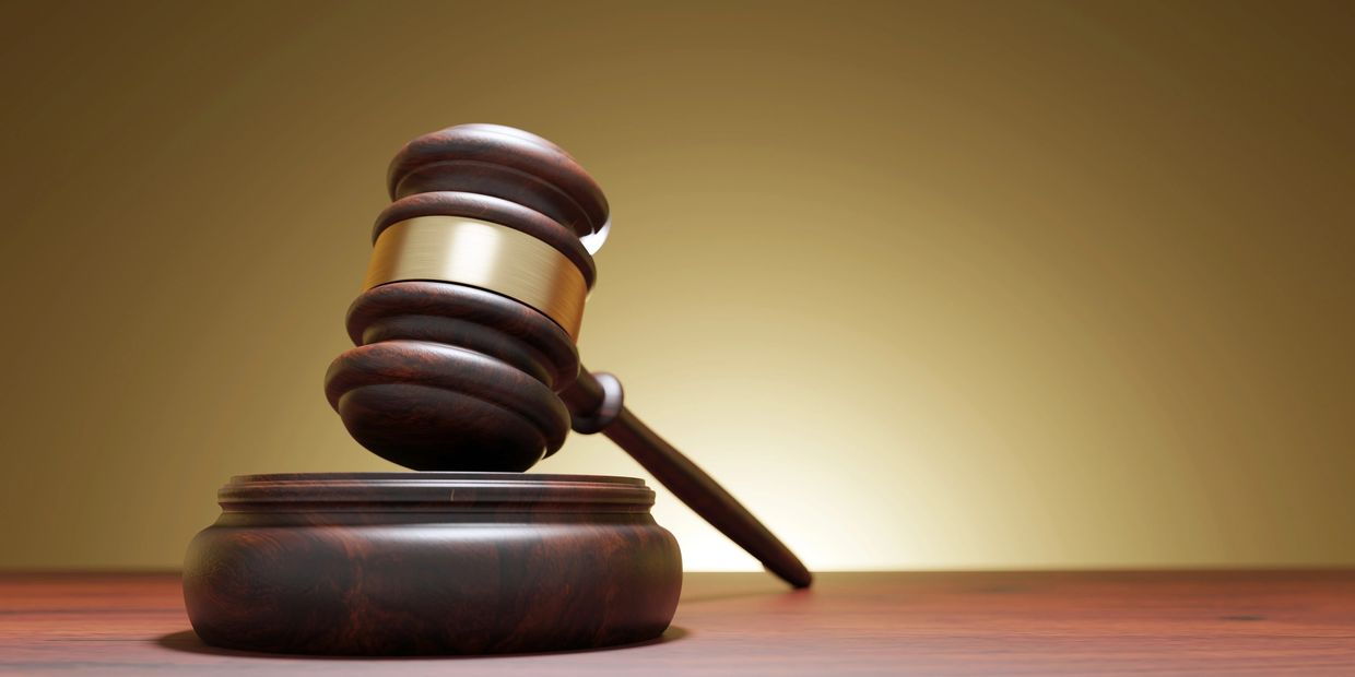 Wooden judge's gavel on a desk with a golden background.