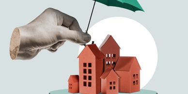 Hand holding umbrella protecting miniature houses, symbolizing home insurance or protection.