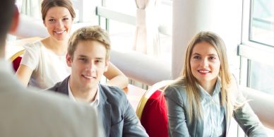 Three young professionals attentively listening in a meeting room with natural light.