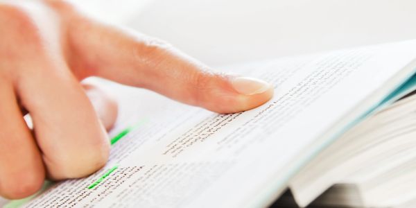 A finger pointing to a highlighted line in a book.