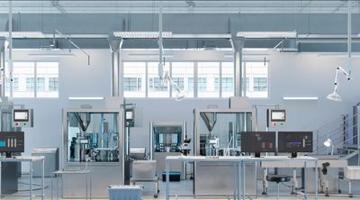 Modern pharmaceutical manufacturing lab with advanced machinery and computer workstations.
