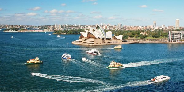 Sydney Opera House with boats in the water on a sunny day.