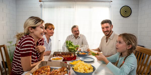 Family enjoying a meal together with pizza and snacks.