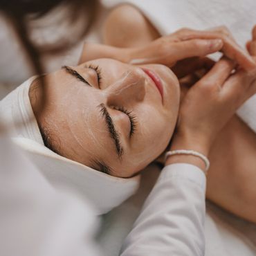 Woman relaxing with facial treatment and massage at a spa.