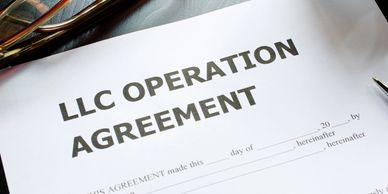 LLC operating agreement on desk with pen, glasses, and coffee mug.
