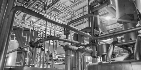 Complex network of industrial stainless steel pipes and tanks in a factory.