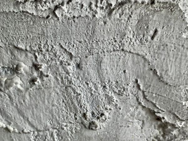 Close-up of a textured, white painted surface with rough patches.