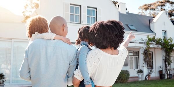 Family admiring their new white house on a sunny day.