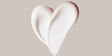 Heart-shaped white cream on beige background.