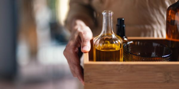 Hand holding a wooden tray with bottles and a bowl.