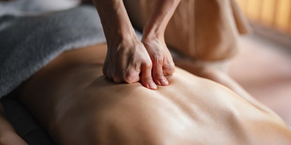 Person receiving a deep tissue back massage with focused pressure.
