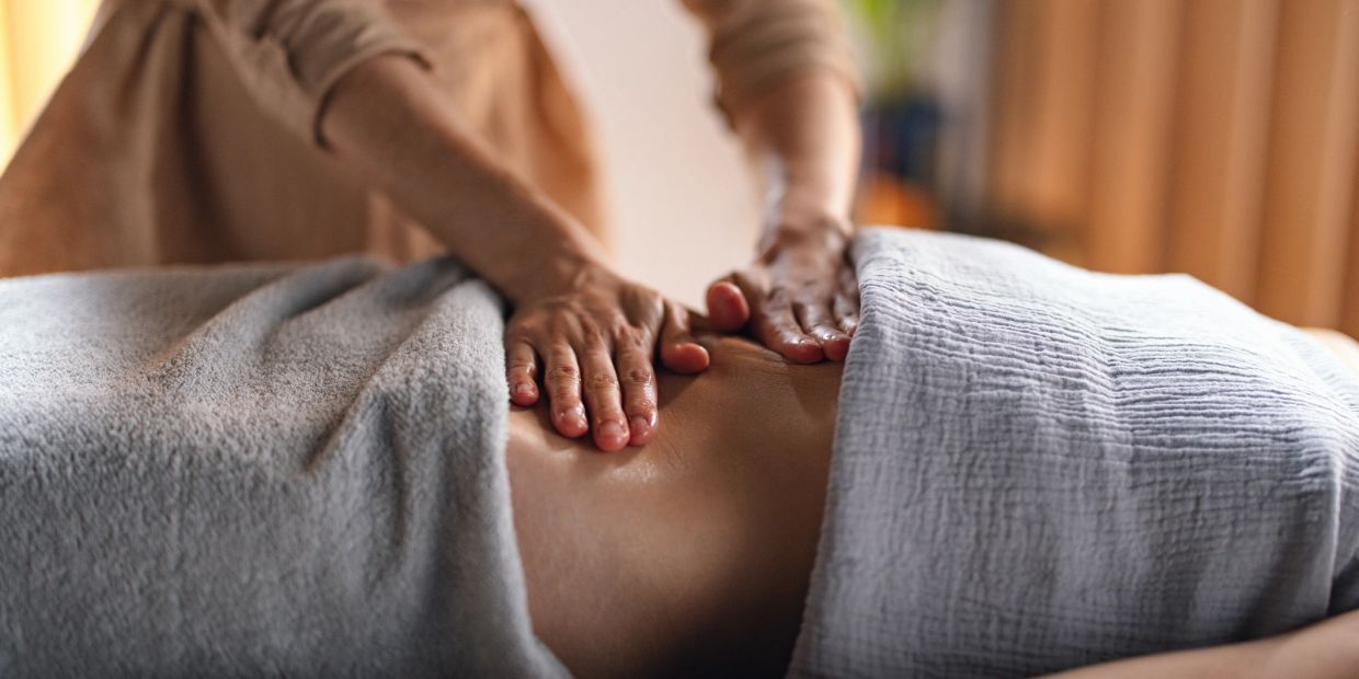 Hands giving a relaxing back massage with towels covering the person.