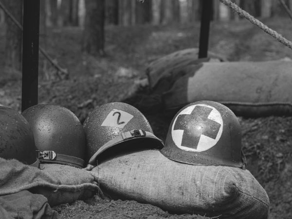 WWII helmets lined on sandbags in a trench.