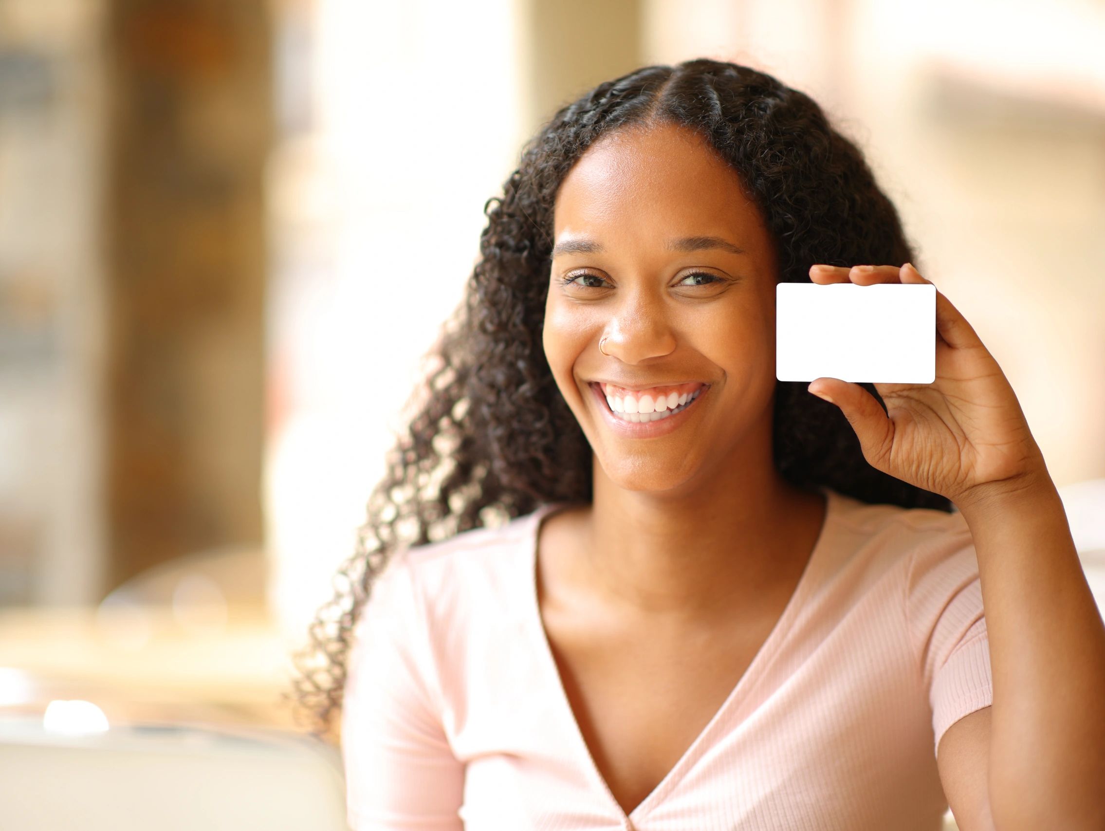 Smiling woman holding a blank white card close to her face.