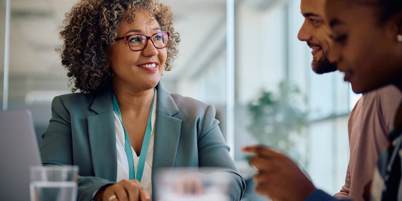 Confident businesswoman smiling during a meeting with colleagues.