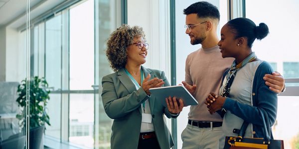 A businesswoman explaining something to a couple with a tablet.