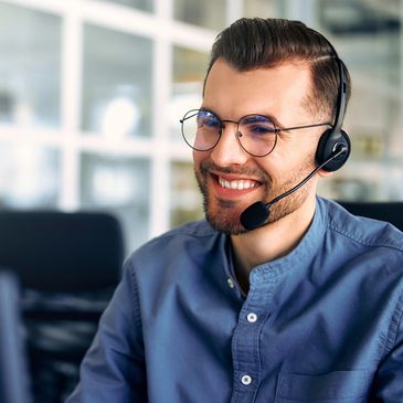 Smiling man wearing headset and glasses at work.