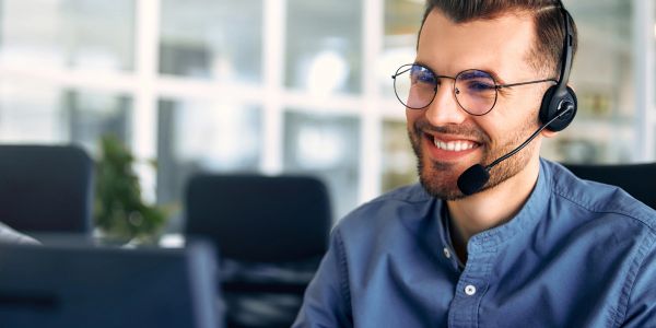Man with headset smiling at computer.