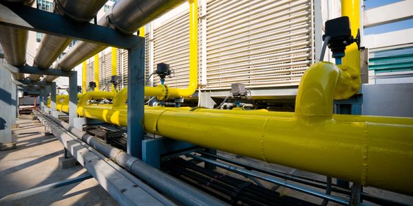 Industrial yellow pipelines with valves in a factory setting.