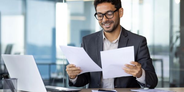 Smiling businessman reviewing documents at desk.