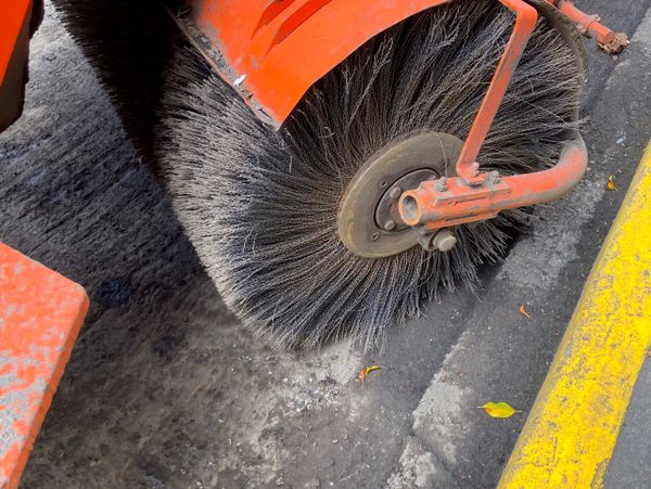 Close-up of a street sweeper's rotating brush cleaning the road.