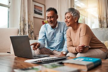 Senior couple using laptop together at home, smiling.