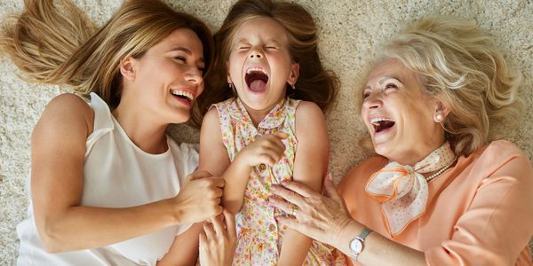 A group of women laying on the ground with one girl laughing.