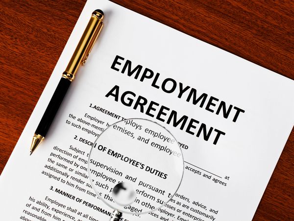 Employment agreement document with a pen on a wooden surface.