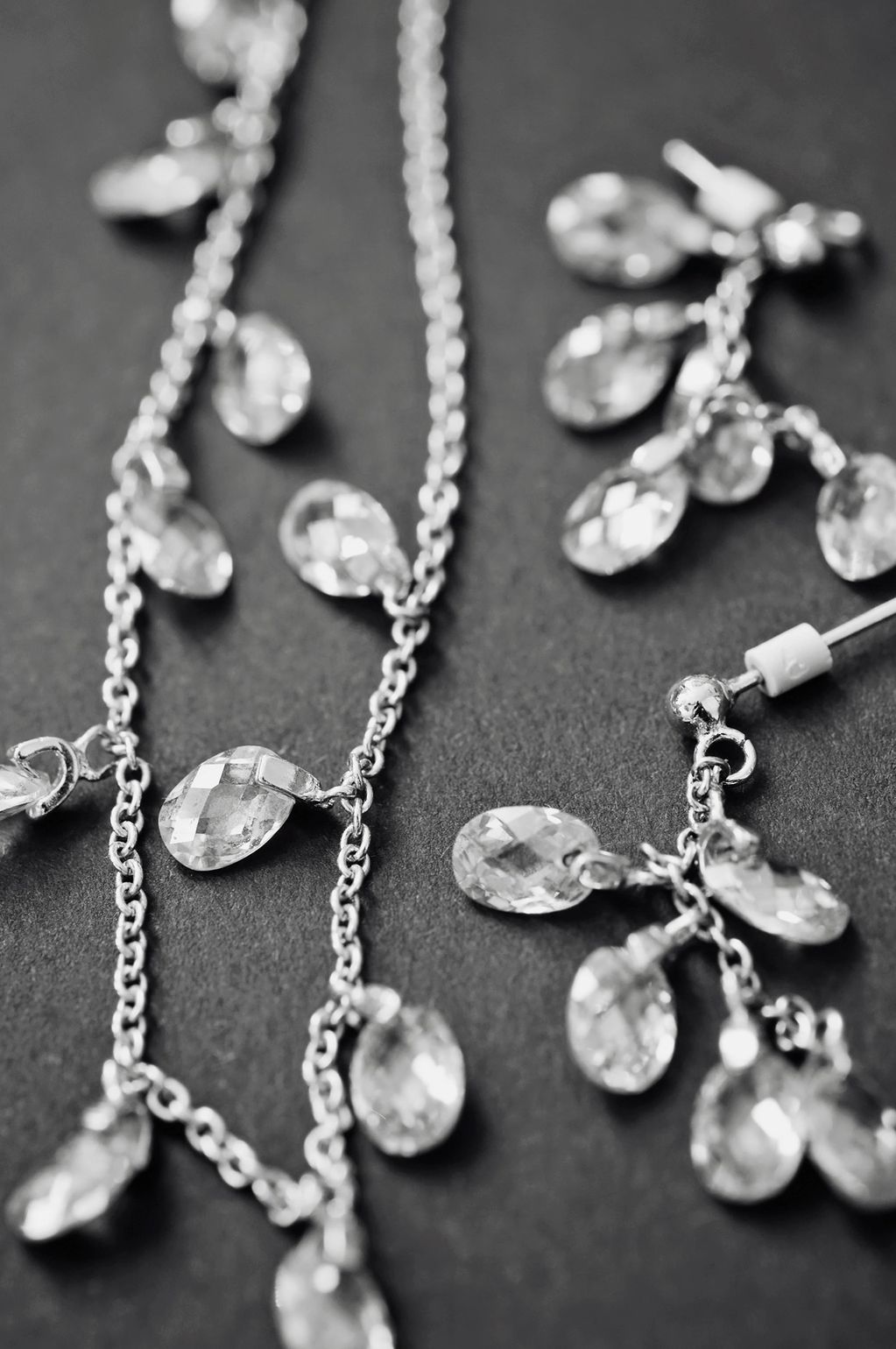 Silver jewelry with crystal-like pendants on a dark surface.