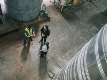 Three people conversing in an industrial setting.