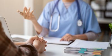 Healthcare professional consulting a patient with medical documents on the table.