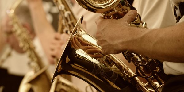 Close-up of musicians playing saxophones in a band.